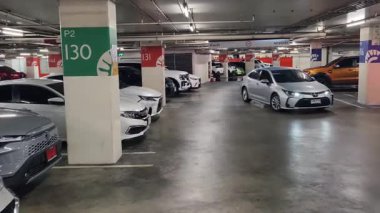 Düzenli olarak dizilmiş çeşitli arabaların sergilendiği modern bir otopark.