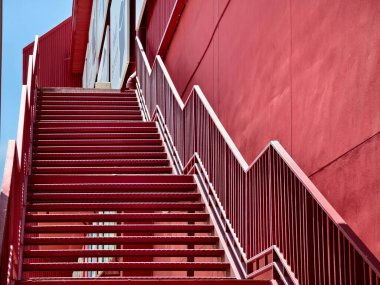 Büyük kırmızı bir duvara tırmanan bir merdiven seti..
