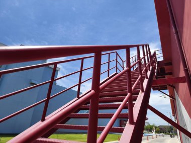 Büyük kırmızı bir duvara tırmanan bir merdiven seti..