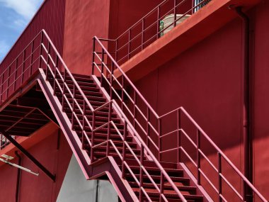 Büyük kırmızı bir duvara tırmanan bir merdiven seti..