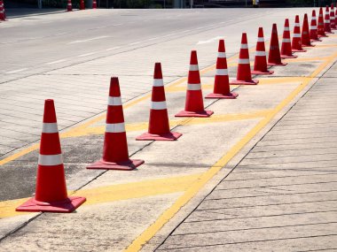 Bir sıra kırmızı ve beyaz trafik konisi bir yol tarafından yerleştirilir..