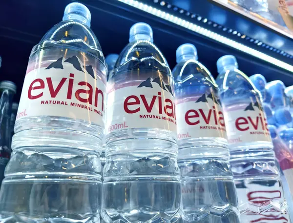 FUKET, THAILAND - 8 Mart 2025: Evian maden suyu şişeleri düzgünce bir rafa dizilmiştir.