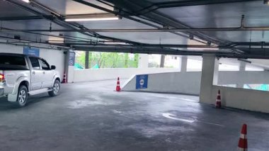 Bir araba, çeşitli koni ve tabelalarla işaretlenmiş park alanından dikkatle geçiyor..