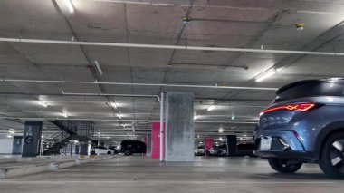 Modern bir elektrikli araç, çağdaş bir otoparkın içine park ediyor..