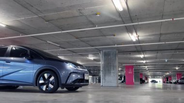 Modern bir elektrikli araç, çağdaş bir otoparkın içine park ediyor..