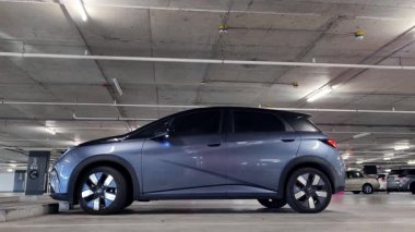 Modern bir elektrikli araç, çağdaş bir otoparkın içine park ediyor..