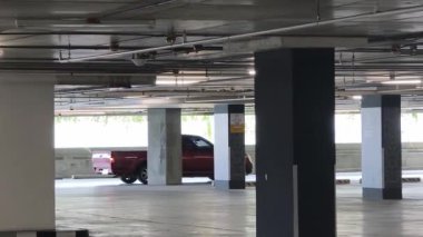 Bir araba, çeşitli koni ve tabelalarla işaretlenmiş park alanından dikkatle geçiyor..