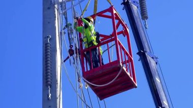  Asansördeki iki yetenekli işçi, uzun direğin elektrik bakımında güvenliği sağlıyorlar..
