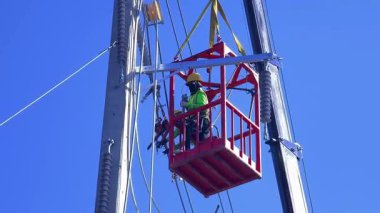  Asansördeki iki yetenekli işçi, uzun direğin elektrik bakımında güvenliği sağlıyorlar..