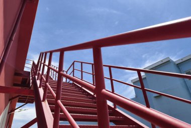 Büyük kırmızı bir duvara tırmanan bir merdiven seti..