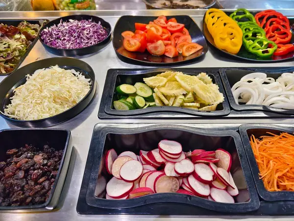 Bol miktarda taze sebze ve meyve içeren bir salata barı..