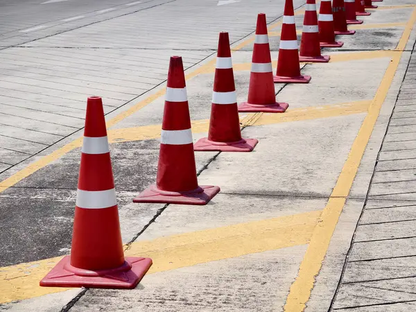 Bir sıra kırmızı ve beyaz trafik konisi bir yol tarafından yerleştirilir..