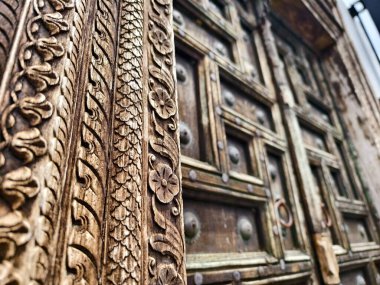 Zarif metal yüzüklerle süslenmiş antik ahşap bir kapının ayrıntılı görüntüsü.