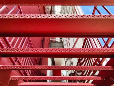 Büyük kırmızı bir duvara tırmanan bir merdiven seti..