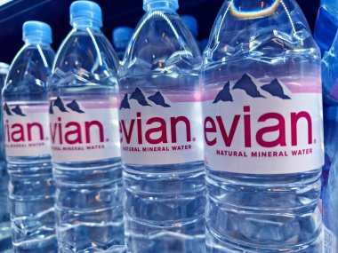 FUKET, THAILAND - 8 Mart 2025: Evian maden suyu şişeleri düzgünce bir rafa dizilmiştir.