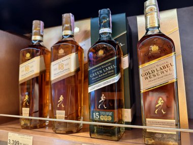 PHUKET, THAILAND - 8 Mart 2025: Bir süpermarketteki rafta Johnnie Walker 'ın viski şişeleri.