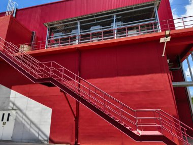 Büyük kırmızı bir duvara tırmanan bir merdiven seti..