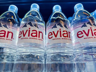 FUKET, THAILAND - 8 Mart 2025: Evian maden suyu şişeleri düzgünce bir rafa dizilmiştir.