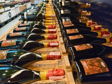 Şampanyaların çeşitleri zarif bir şekilde ahşap bir rafta dizilmiştir..