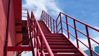 Büyük kırmızı bir duvara tırmanan bir merdiven seti..