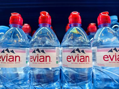FUKET, THAILAND - 8 Mart 2025: Evian maden suyu şişeleri düzgünce bir rafa dizilmiştir.