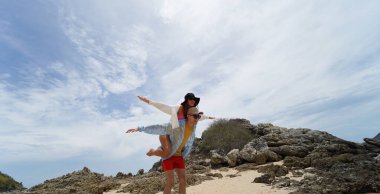 Genç bir çift kumsalda boş boş yürüyor, el ele tutuşuyor ve sıcak güneşin tadını çıkarıyor..