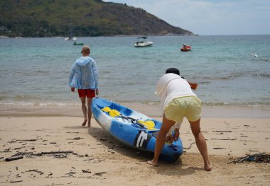 Genç bir çift deniz yolculuğu için mavi bir kano fırlatıyor..