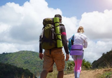 Genç bir çift okyanus manzarası sunan engebeli kayalık bir uçurumda yürüyüş yapıyor..