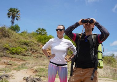 Bir erkek ve bir kadın dikkatle dürbünle uzaktan ilginç bir şeye bakıyorlar..