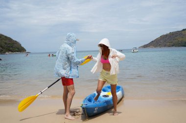 Genç bir çift deniz yolculuğundan sonra sudan bir kano çıkarıyorlar..