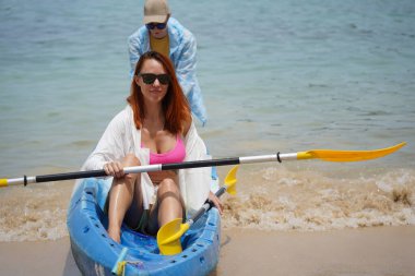 Genç bir çift deniz yolculuğu için mavi bir kano fırlatıyor..