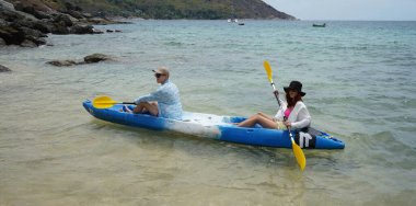 Genç çift, açık mavi bir kanoyla birlikte sarı raketlerle mutlu bir şekilde yol alıyorlar..