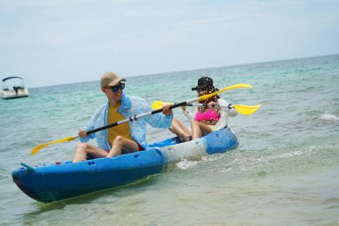 Genç çift, açık mavi bir kanoyla birlikte sarı raketlerle mutlu bir şekilde yol alıyorlar..