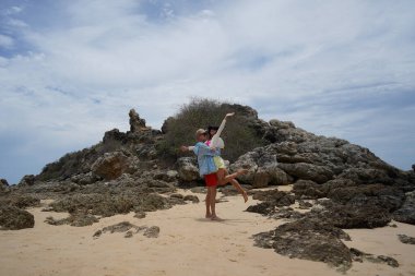 Genç bir çift kumsalda boş boş yürüyor, el ele tutuşuyor ve sıcak güneşin tadını çıkarıyor..