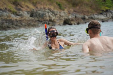 Bir adam ve bir kadın gözlük takıyor ve suyun tadını çıkarıyorlar..