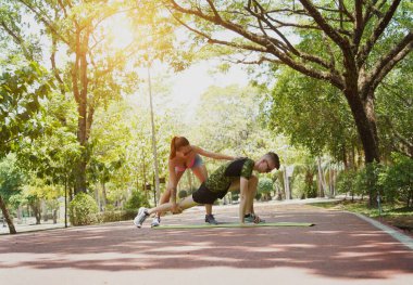 Bir adam ve bir kadın parkta birlikte koştuktan sonra bacaklarını açıyorlar..