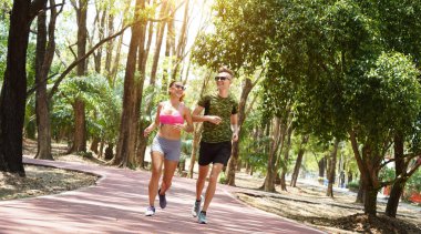 Bir adam ve bir kadın güzel bir parkta birlikte koşuyorlar, temiz havanın tadını çıkarıyorlar.