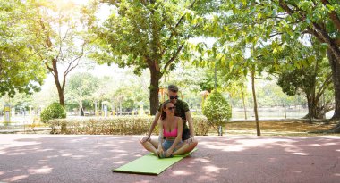 Renkli bir yoga minderinde bacaklarını açarken bir erkek bir kadına yardım ediyor..