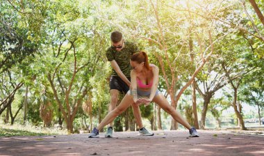 Bir adam ve bir kadın parkta birlikte koştuktan sonra bacaklarını açıyorlar..