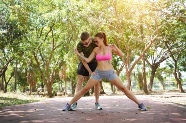 Bir adam ve bir kadın parkta birlikte koştuktan sonra bacaklarını açıyorlar..