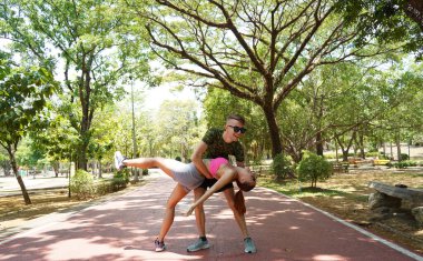 Renkli bir yoga minderinde bacaklarını açarken bir erkek bir kadına yardım ediyor..