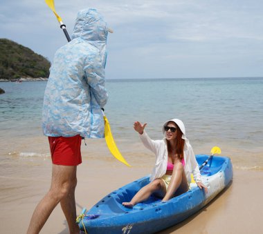 Genç bir çift deniz yolculuğundan sonra sudan bir kano çıkarıyorlar..