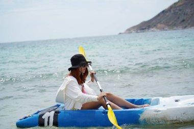 Genç çift, açık mavi bir kanoyla birlikte sarı raketlerle mutlu bir şekilde yol alıyorlar..