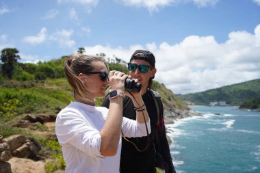 Bir erkek ve bir kadın dikkatle dürbünle uzaktan ilginç bir şeye bakıyorlar..