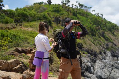 Bir erkek ve bir kadın dikkatle dürbünle uzaktan ilginç bir şeye bakıyorlar..