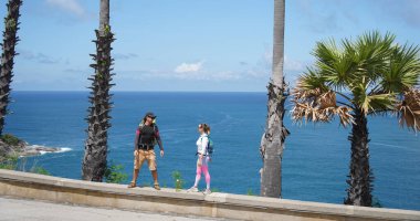 Muhteşem palmiye ağaçlarının önünde genç bir çift yan yana duruyor..