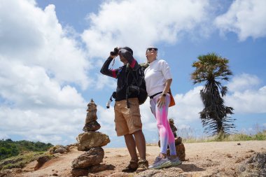 Bir erkek ve bir kadın dikkatle dürbünle uzaktan ilginç bir şeye bakıyorlar..