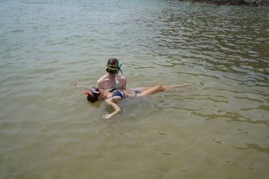 Bir adam ve bir kadın gözlük takıyor ve suyun tadını çıkarıyorlar..