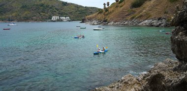 Genç çift, açık mavi bir kanoyla birlikte sarı raketlerle mutlu bir şekilde yol alıyorlar..
