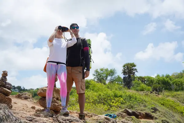 Bir erkek ve bir kadın dikkatle dürbünle uzaktan ilginç bir şeye bakıyorlar..